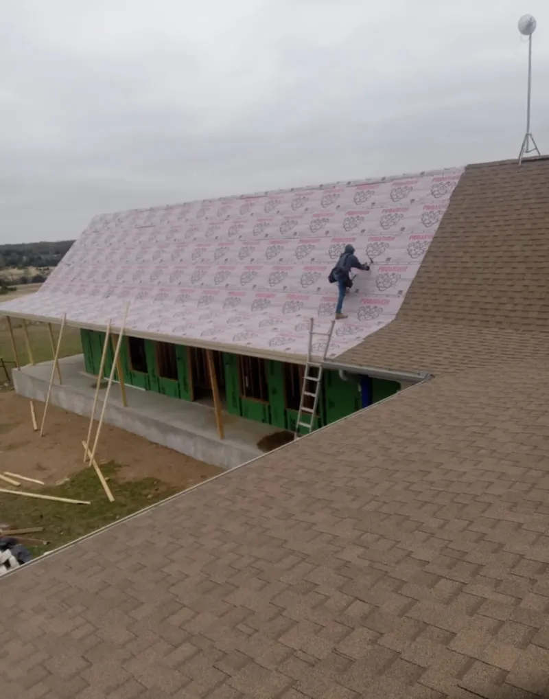 Worker preparing underlayment for a metal roof installation in Millcreek